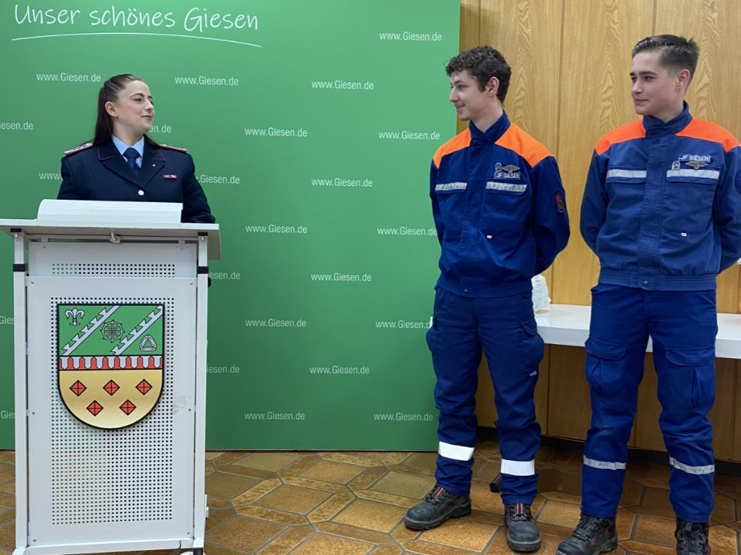Jugendfeuerwehrwartin Cecilia Porsch gratuliert Aaron Smith und Hendrik Fiege zur bestandenen Truppmann Teil 1 Ausbildung